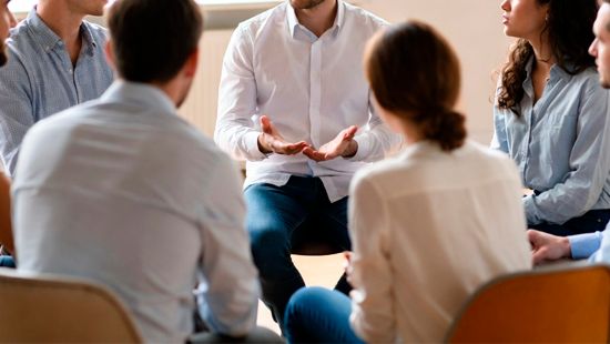 Группа в кругу обсуждает тему, мужчина жестикулирует